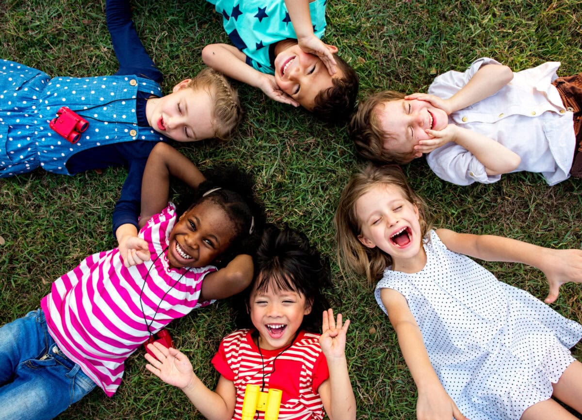 Group of kindergarten kids lying on the grass at park and relax Group of kindergarten kids lying on the grass at park and relax with smiling