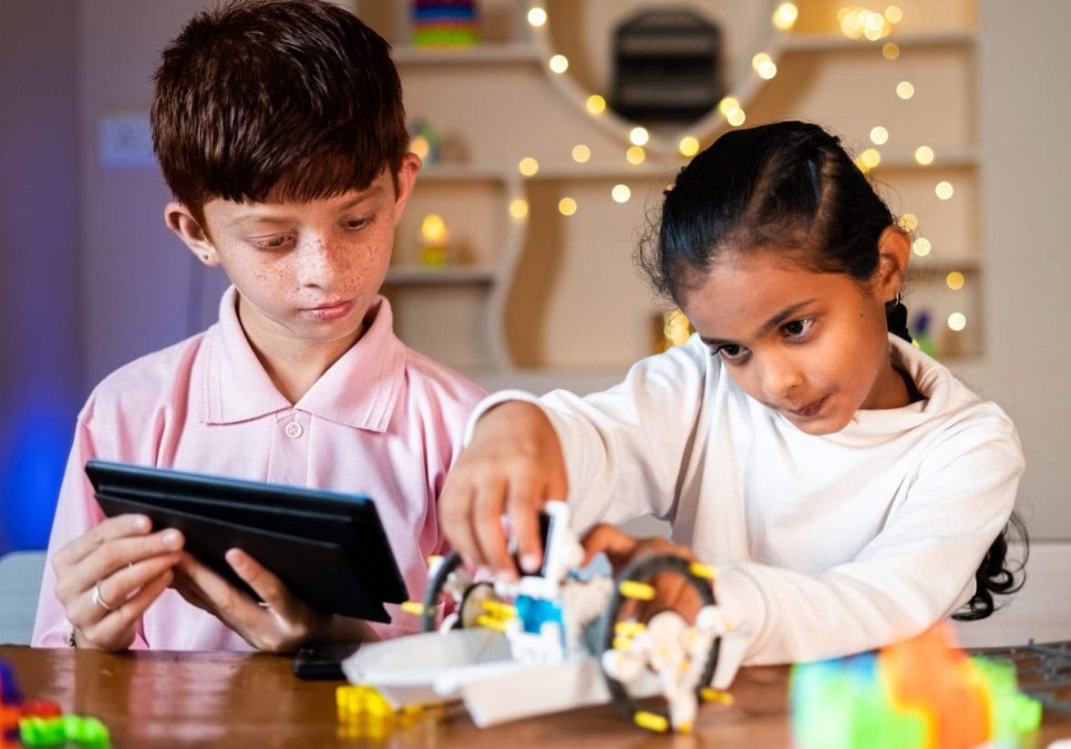 Kids busy making DIY robot by looking from digital tablet at home concept of Children robotic Experiment, togetherness, childhood learning and development